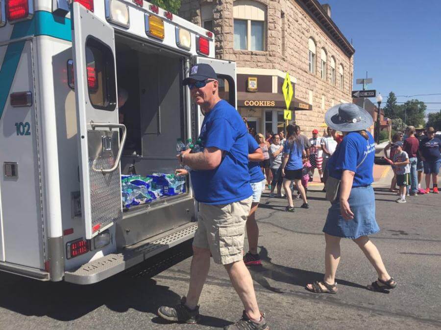 people handing out waters from the back of an ambulance in the parade