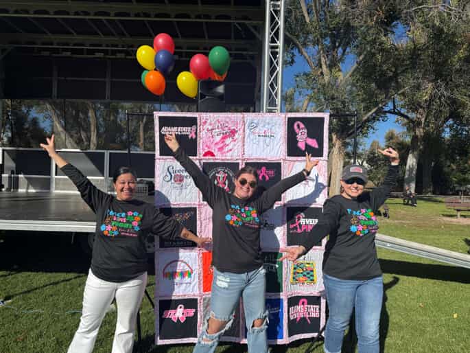 volunteers in front of quilt